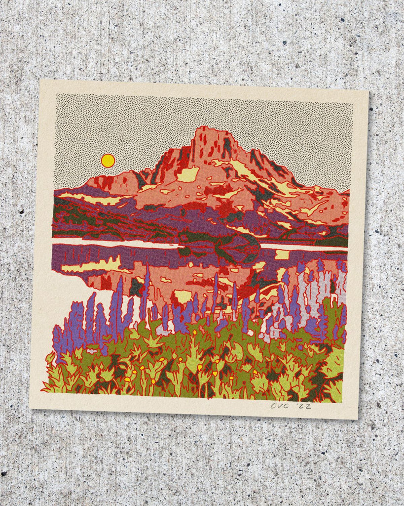 One of the artist designed postcards showing a mountain scene. Purple and green flowers line the foreground, reflective water fills the middle ground, and a rigid salmon and purple mountain is in the background. The sky is white with small black dots and a bigger yellow dot for the sun.  