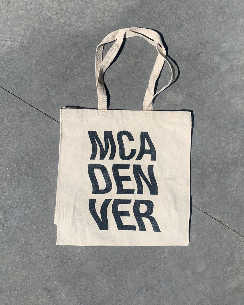 MCA Denver Wavy Tote is photographed on a cement background. 