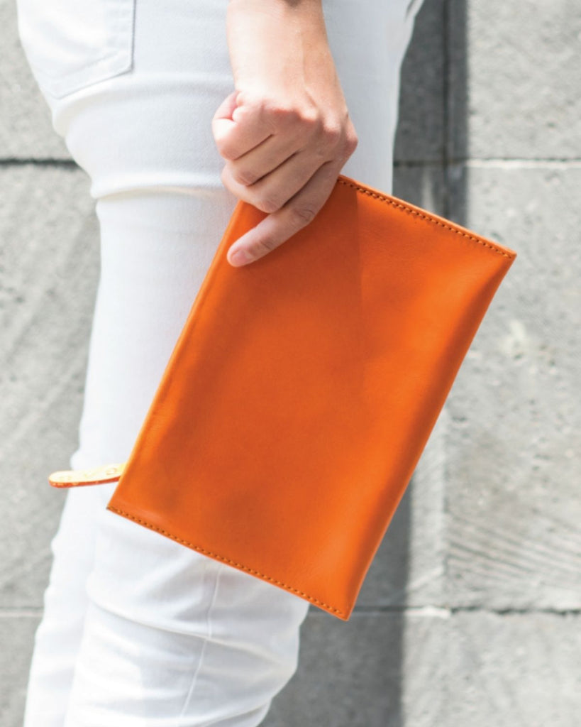 The orange leather pouch carried by model. 