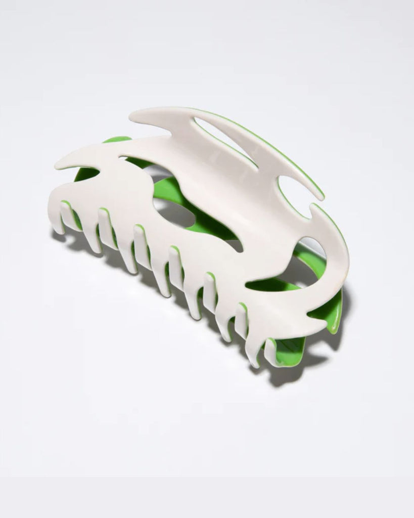 White claw clip with abstract shape cutouts. Inside of clip is lime green and shows through the cutouts. 