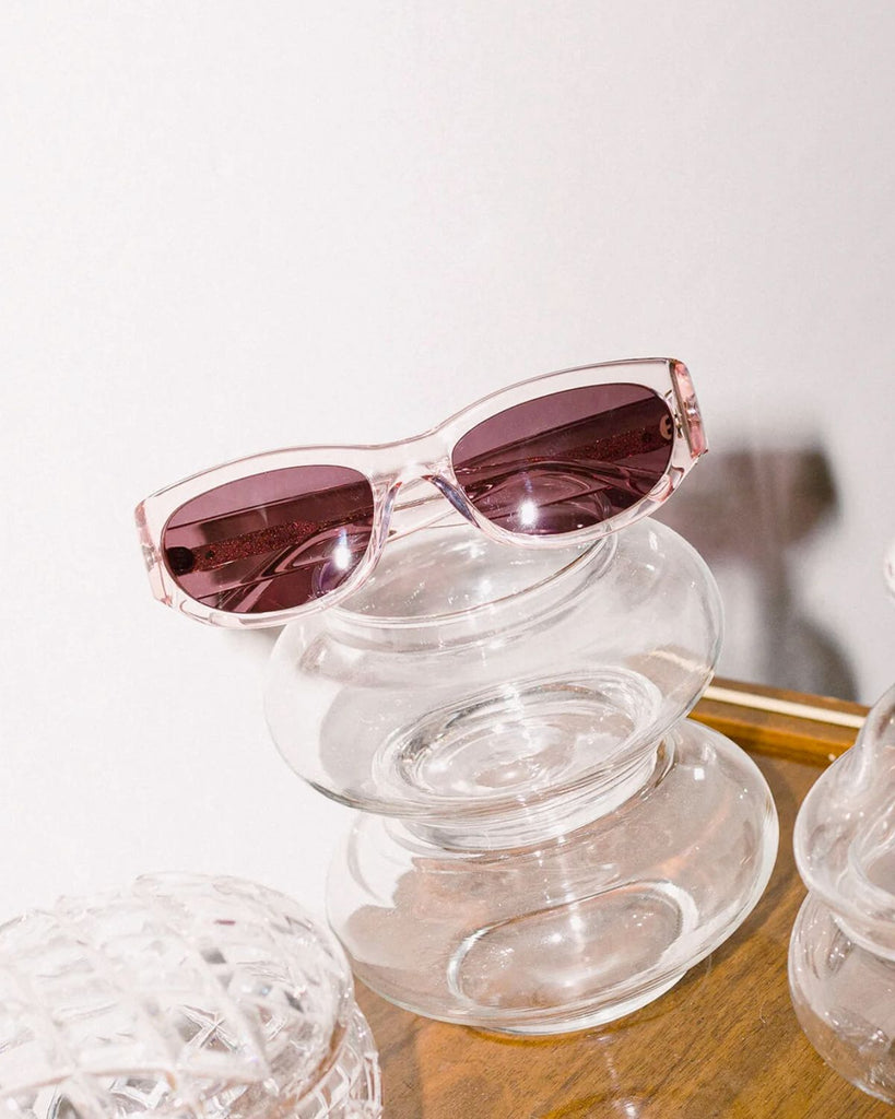 The Funk Punk sunglasses on glass bowls atop a wooden table. 