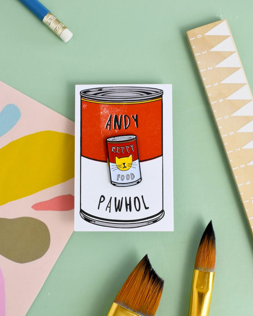 Andy Warhol inspired cat pin with art supplies surrounding it. 