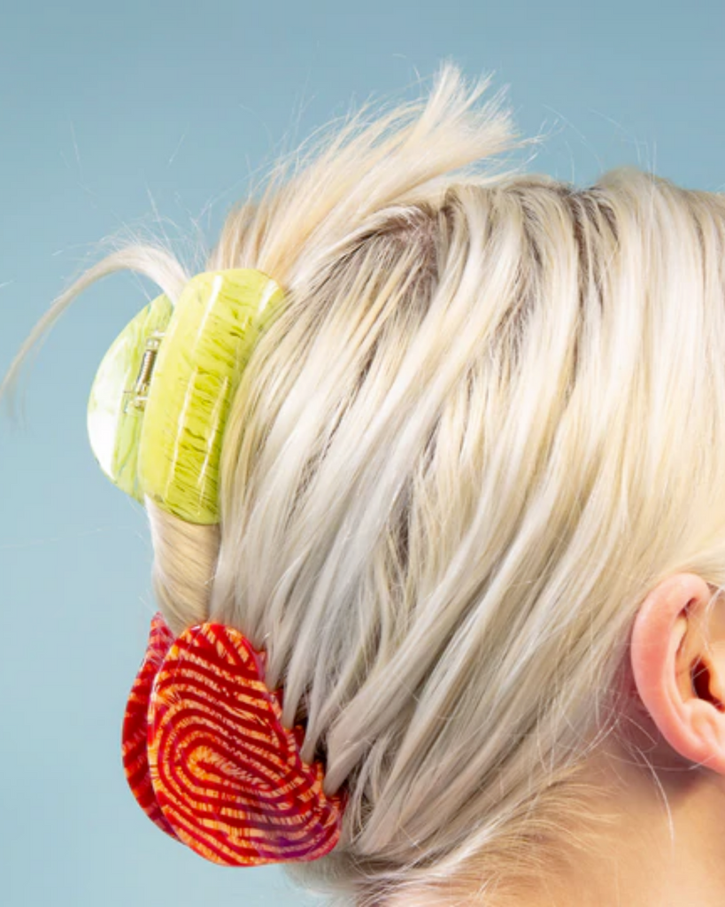 Medium sized red/orange and yellow claw clips stacked and holding blond hair in an updo.