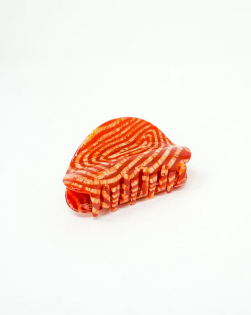 Redwood claw clip has a red and orange striped pattern. Shown with a white backdrop