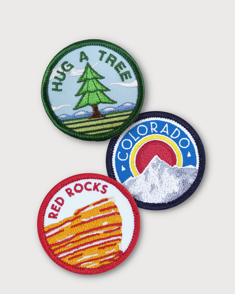 Three different colorado pride patches made by Coloradical. The 'hug a tree' patch is on top and 2 other patches are piled together. 