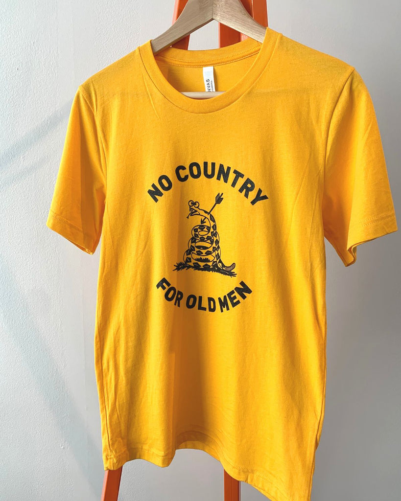 Bright yellow/mustard t-shirt on a hanger against a white wall. 