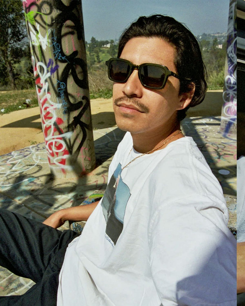 The same model wearing the sunglasses at a skatepark. 