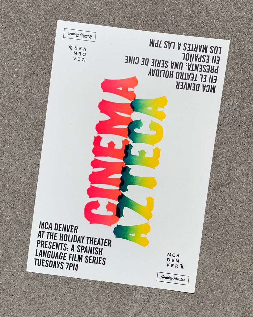 Poster has black text on the bottom left corner that describes the event. The same text but in Spanish is mirrored on the top right corner. Cinema Azteca is spelled out vertically in the middle. 'Cinema' is red and 'Azteca' is a gradient of green to yellow. The poster is white and is shown on a cement surface. 