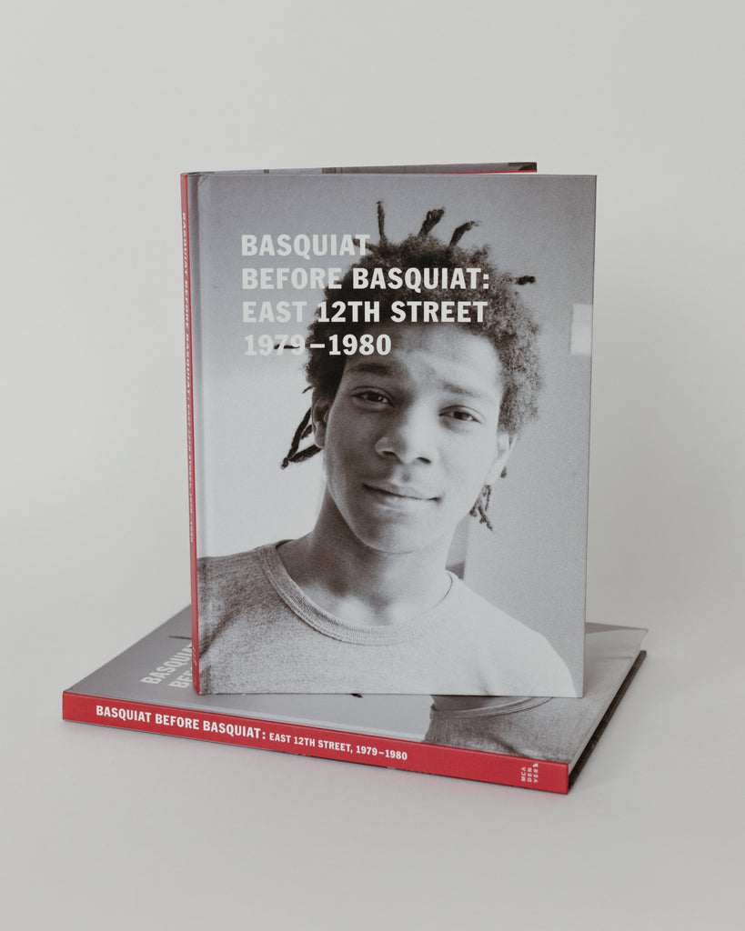 Basquiat Catalogue for MCA Denver on a white backdrop. The book shows Basquiat's portrait in black and white. 