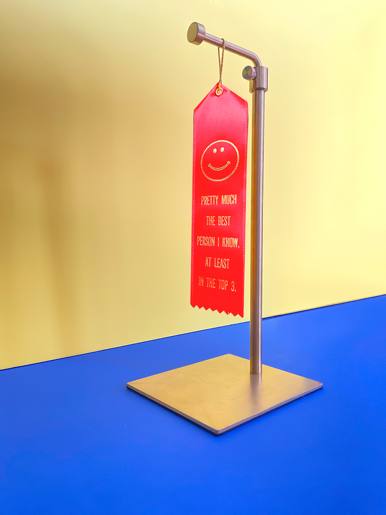 The red colorway shown on a gold stand with a blue surface and a yellow background. 